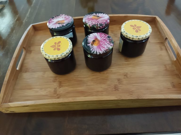 Cinq pots de confiture sur un plateau en bois.